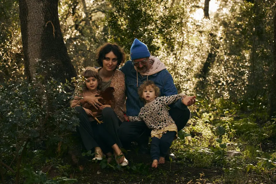 ema, tomas and their children sitting together among the trees in the late afternoon light