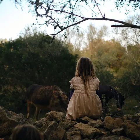 one of the children walking through the field with the pony